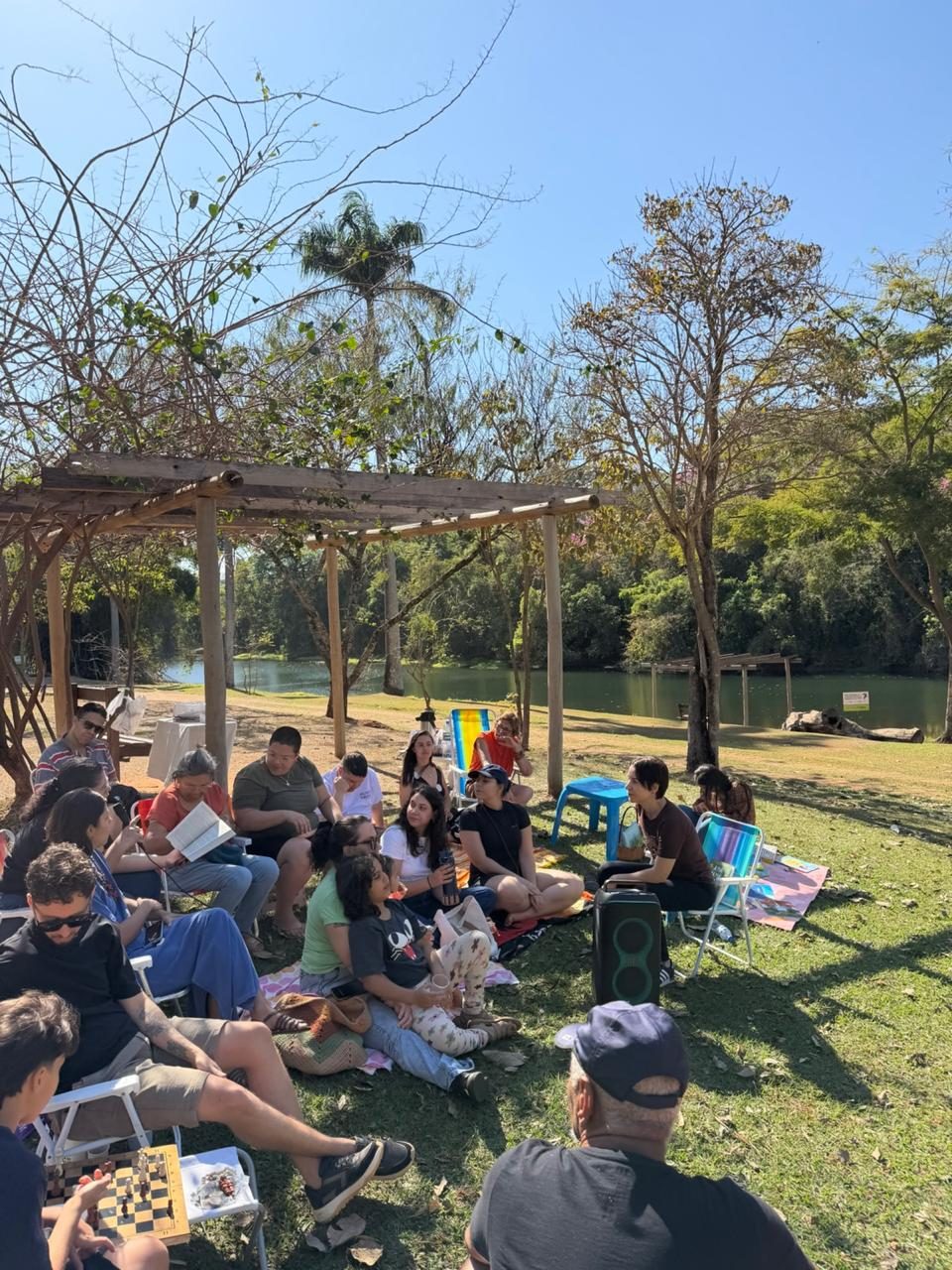 Roda de leitura reunida sob a pérgola à beira do lago do Jardim Botânico