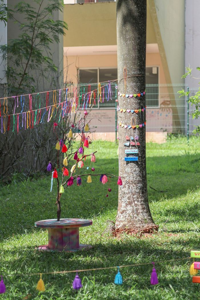 Galho decorado com tassels coloridos sobre carretel pintado