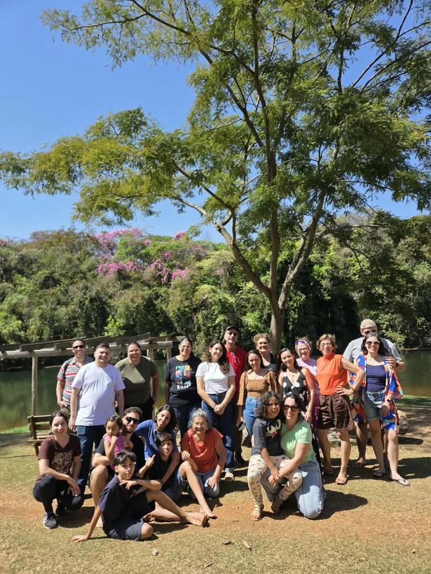 Foto de grupo dos participantes sob uma árvore, com ipês floridos ao fundo