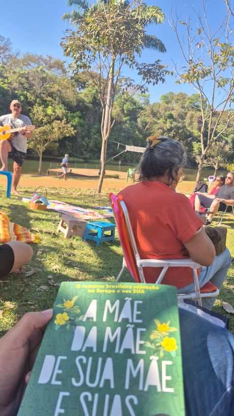 Participante toca violão para a roda, com o livro em primeiro plano