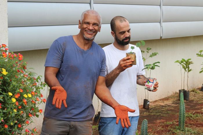 Dois extensionistas sorrindo segurando mudas nativas