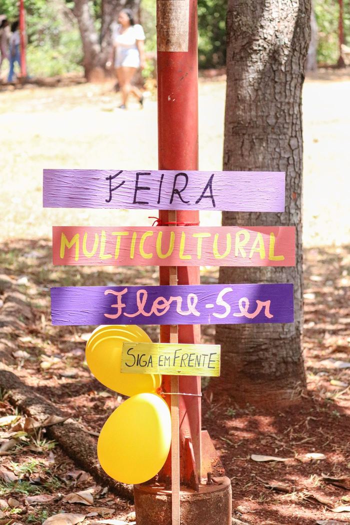 Placa pintada à mão indicando a Feira Multicultural Flore-Ser